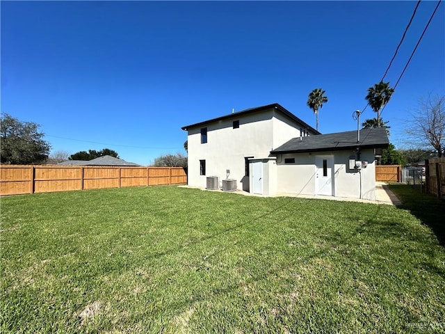 rear view of property featuring central air condition unit, a fenced backyard, a yard, and stucco siding