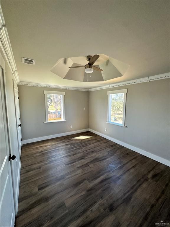 unfurnished room featuring dark wood-style flooring, crown molding, a raised ceiling, visible vents, and baseboards