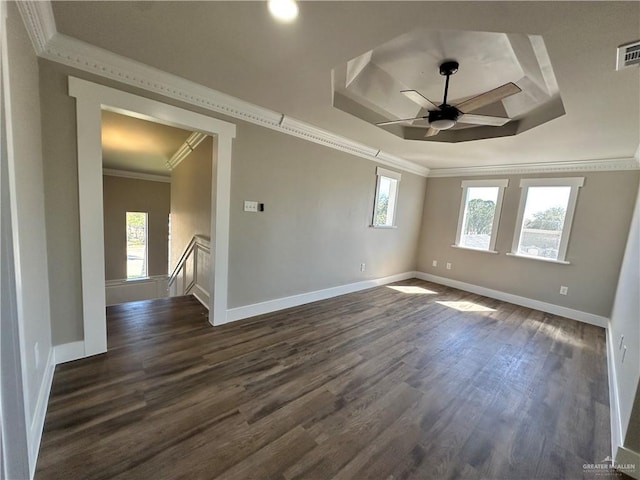 empty room with baseboards, a raised ceiling, ceiling fan, ornamental molding, and dark wood-type flooring