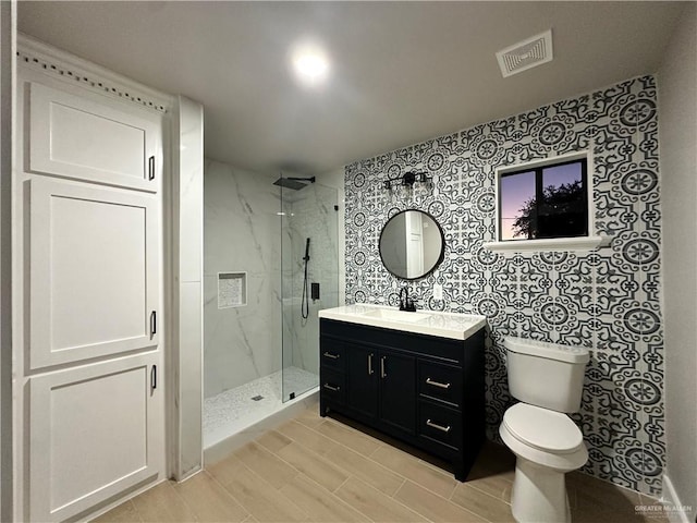 bathroom with toilet, a marble finish shower, vanity, and visible vents