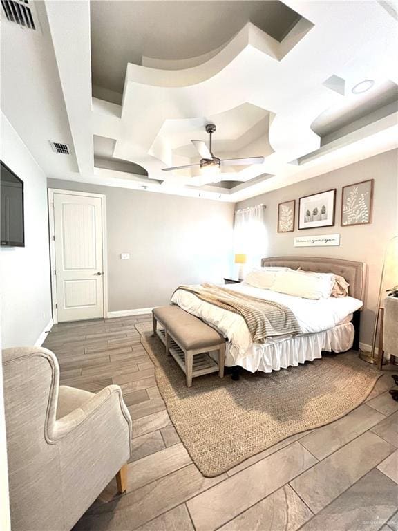 bedroom with ceiling fan and a raised ceiling