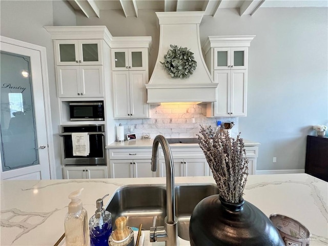 kitchen featuring white cabinets, appliances with stainless steel finishes, custom range hood, and tasteful backsplash