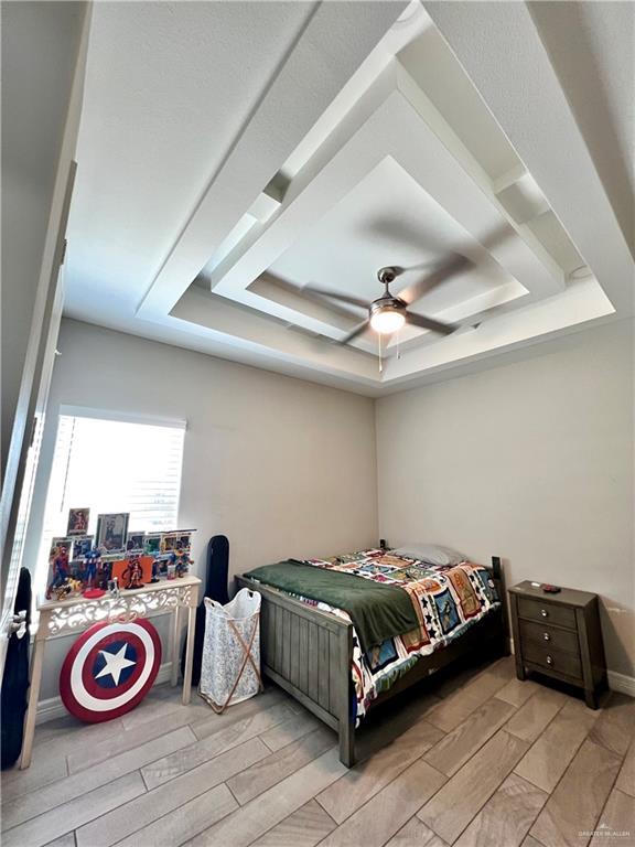 bedroom with ceiling fan and a tray ceiling