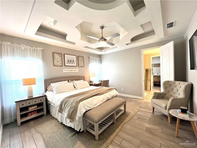 bedroom featuring ceiling fan, a tray ceiling, and multiple windows