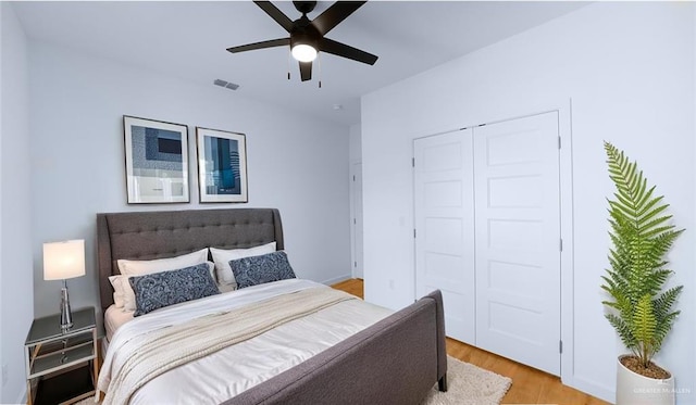 bedroom with a ceiling fan, visible vents, light wood finished floors, and a closet
