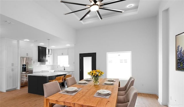 dining room with light wood-style floors, baseboards, ceiling fan, recessed lighting, and a tray ceiling