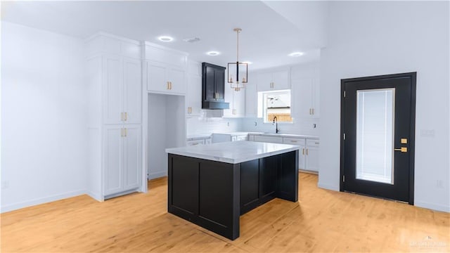 kitchen with white cabinets, hanging light fixtures, decorative backsplash, and light wood-type flooring