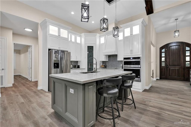 kitchen featuring an island with sink, appliances with stainless steel finishes, tasteful backsplash, light stone counters, and white cabinetry