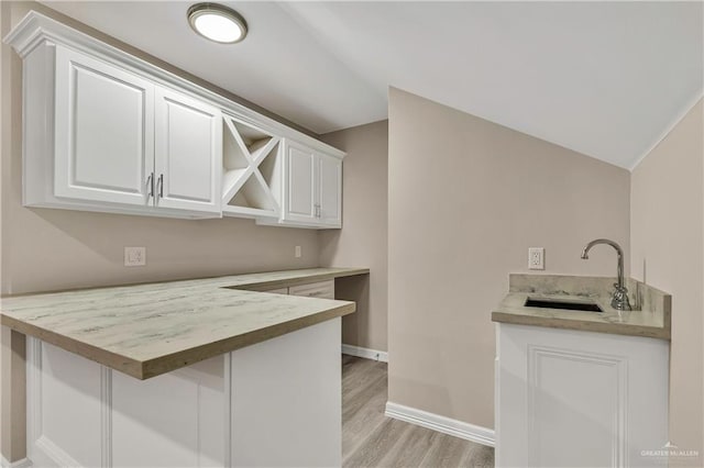 bar featuring white cabinets, light hardwood / wood-style floors, and sink