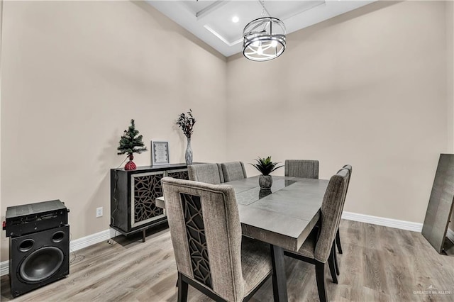 dining area with light hardwood / wood-style floors, an inviting chandelier, and coffered ceiling