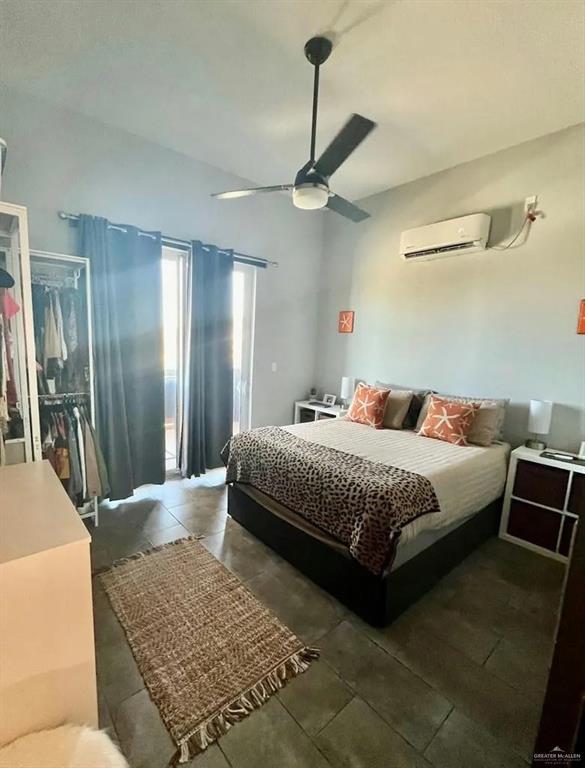 bedroom featuring dark tile patterned flooring, a wall unit AC, and ceiling fan