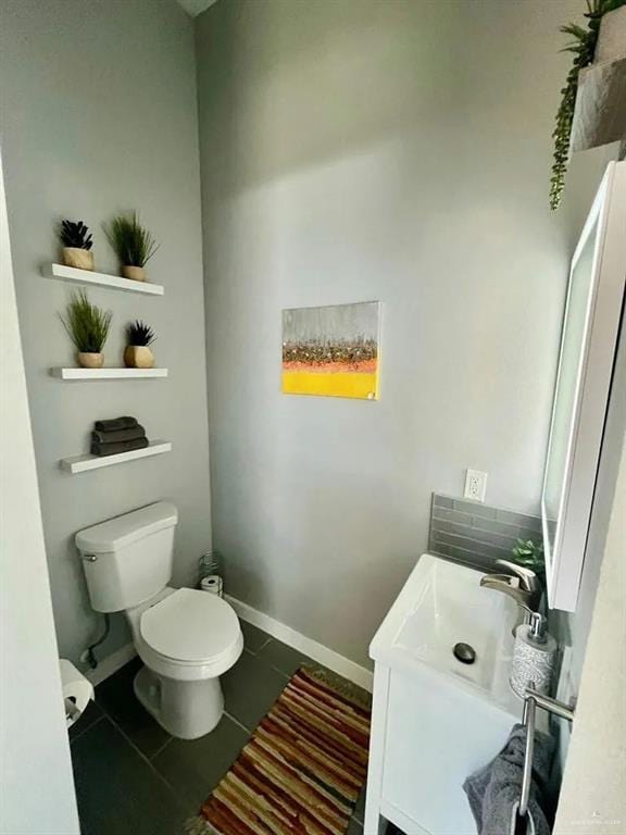 bathroom featuring toilet, vanity, baseboards, and tile patterned floors