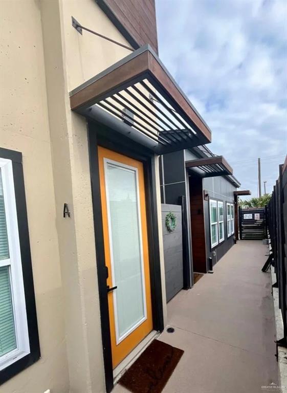 doorway to property featuring fence and stucco siding