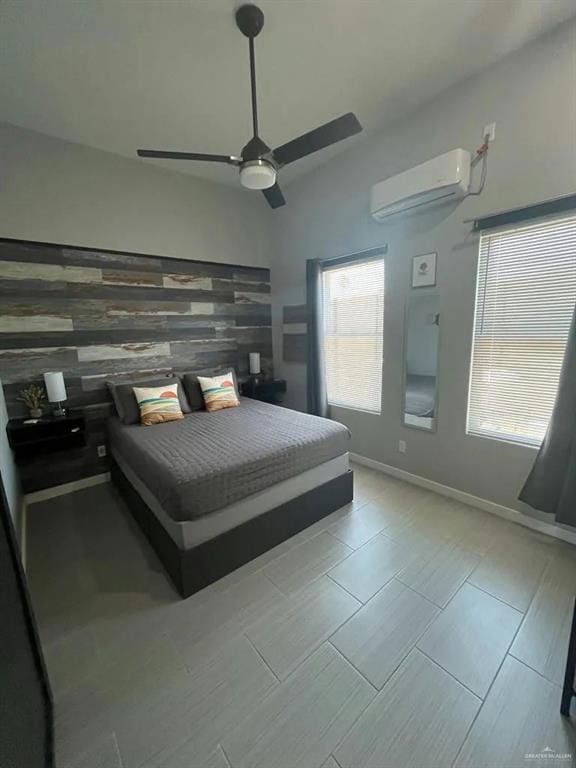 bedroom featuring ceiling fan, lofted ceiling, an accent wall, baseboards, and a wall mounted air conditioner