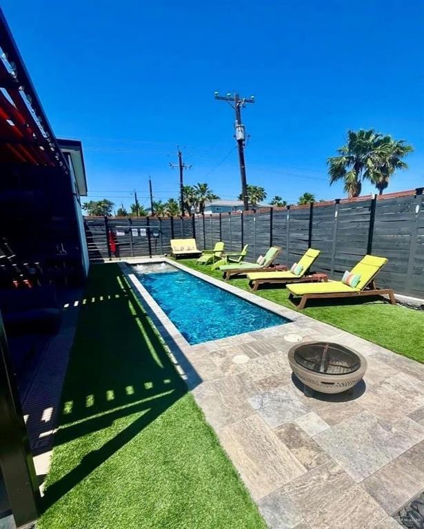 view of swimming pool featuring a fire pit, fence, a yard, a fenced in pool, and a patio area