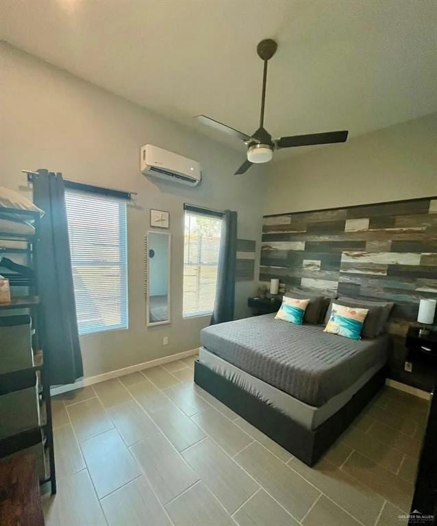 bedroom with a ceiling fan, a wall mounted air conditioner, and baseboards