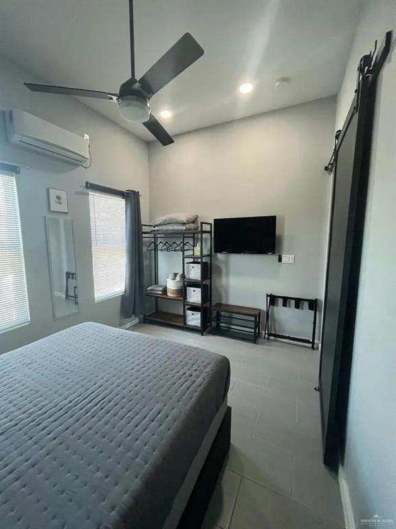 bedroom with a barn door, recessed lighting, a ceiling fan, a wall mounted AC, and tile patterned floors