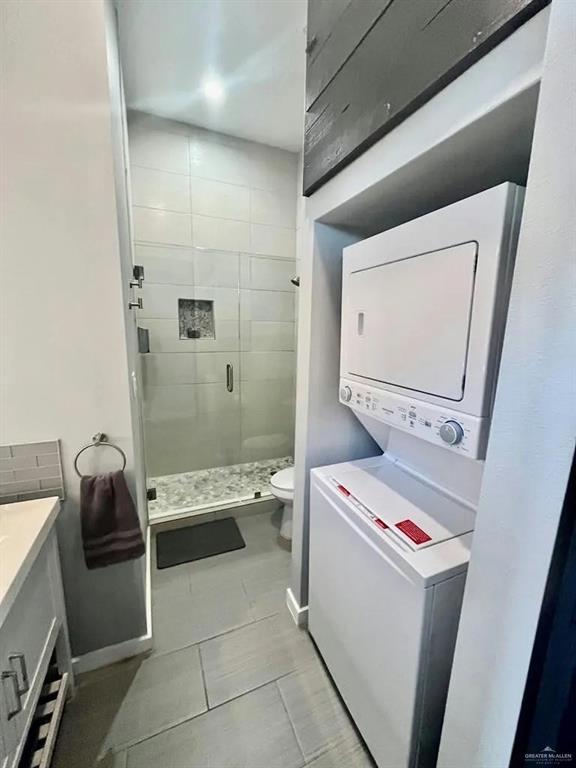 laundry area featuring laundry area, baseboards, and stacked washer / dryer