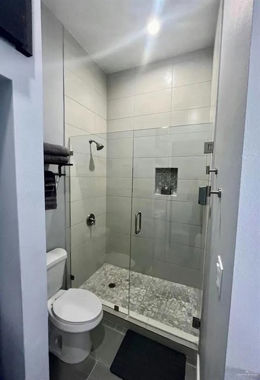 full bath with toilet, a stall shower, and tile patterned floors