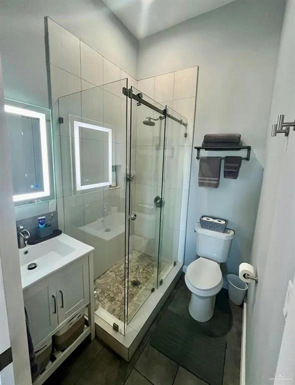 full bath with a stall shower, tile patterned flooring, vanity, and toilet