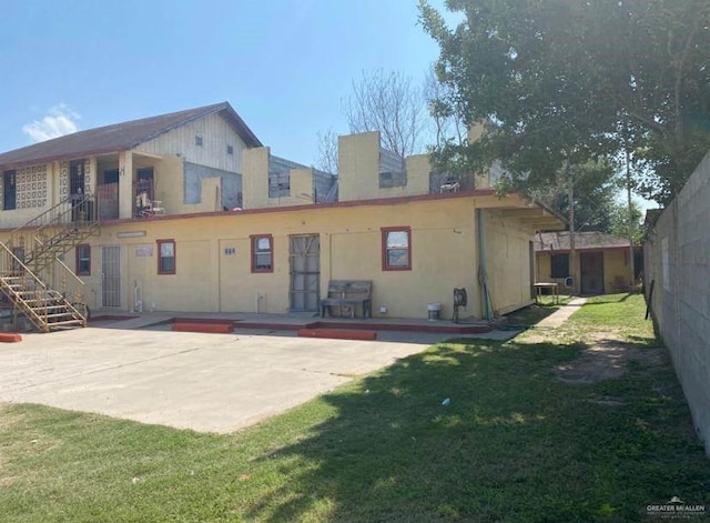 rear view of property with a patio and a lawn