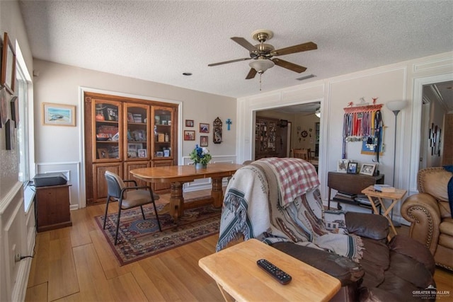 dining space featuring ceiling fan, light wood-type flooring, and a textured ceiling