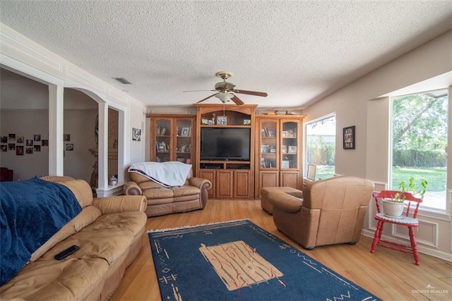 living room featuring a textured ceiling, hardwood / wood-style flooring, a wealth of natural light, and ceiling fan