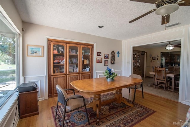 dining area with a textured ceiling, light hardwood / wood-style floors, and ceiling fan