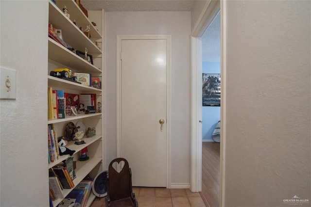 hallway with light tile patterned flooring and a textured ceiling