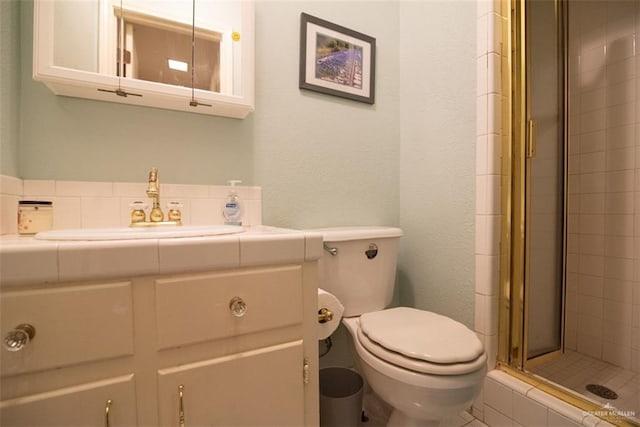 bathroom featuring vanity, toilet, and a shower with door