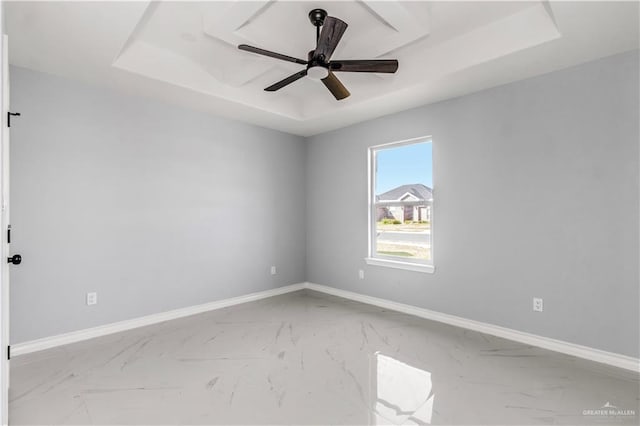 empty room with a raised ceiling and ceiling fan