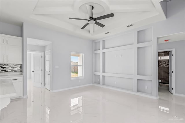 interior space featuring ceiling fan, a tray ceiling, and ensuite bath