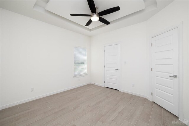 901 E Yuma Ave Unit 606, Mcallen, TX 78503 - unfurnished room featuring baseboards, ceiling fan, a tray ceiling, and light wood-style flooring