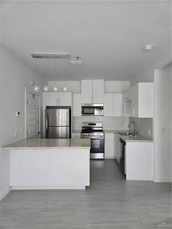 901 E Yuma Ave Unit 606, Mcallen, TX 78503 - kitchen featuring appliances with stainless steel finishes, tasteful backsplash, a sink, light countertops, and white cabinets