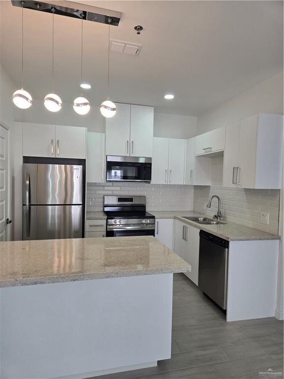 901 E Yuma Ave Unit 606, Mcallen, TX 78503 - kitchen featuring visible vents, a sink, light stone counters, white cabinets, and stainless steel appliances