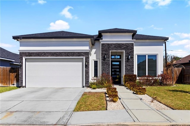 prairie-style house with concrete driveway, stone siding, an attached garage, fence, and stucco siding