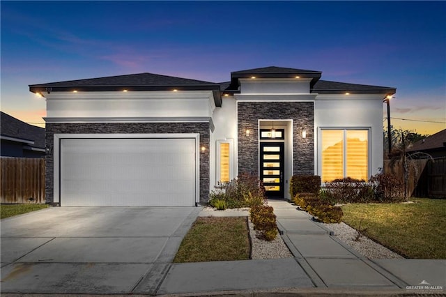 prairie-style home featuring fence, concrete driveway, and stucco siding