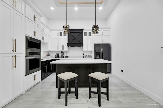 kitchen with stainless steel appliances, white cabinets, a kitchen island, hanging light fixtures, and a breakfast bar area