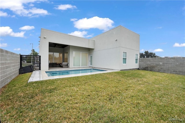 rear view of house featuring a lawn, a patio area, and a fenced in pool