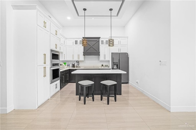 kitchen with pendant lighting, white cabinets, a kitchen breakfast bar, a kitchen island, and stainless steel appliances