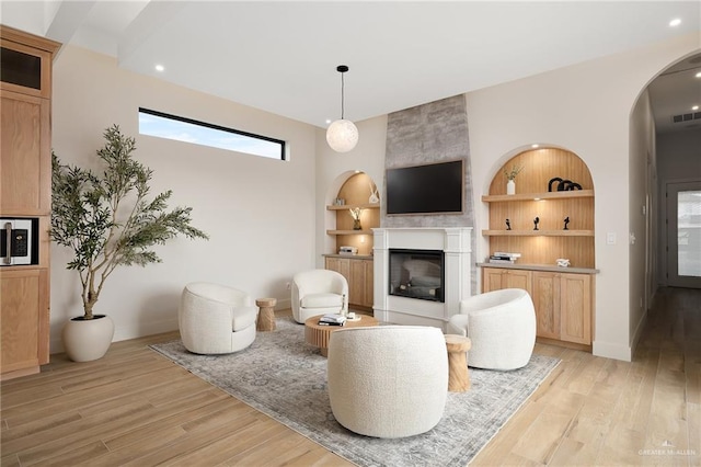 interior space featuring built in features, baseboards, light wood-style flooring, and a fireplace