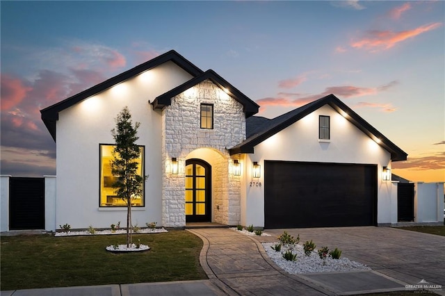 view of front of house featuring a front yard, decorative driveway, stone siding, and stucco siding