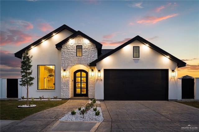 view of front of home featuring a front lawn, stucco siding, decorative driveway, a garage, and stone siding