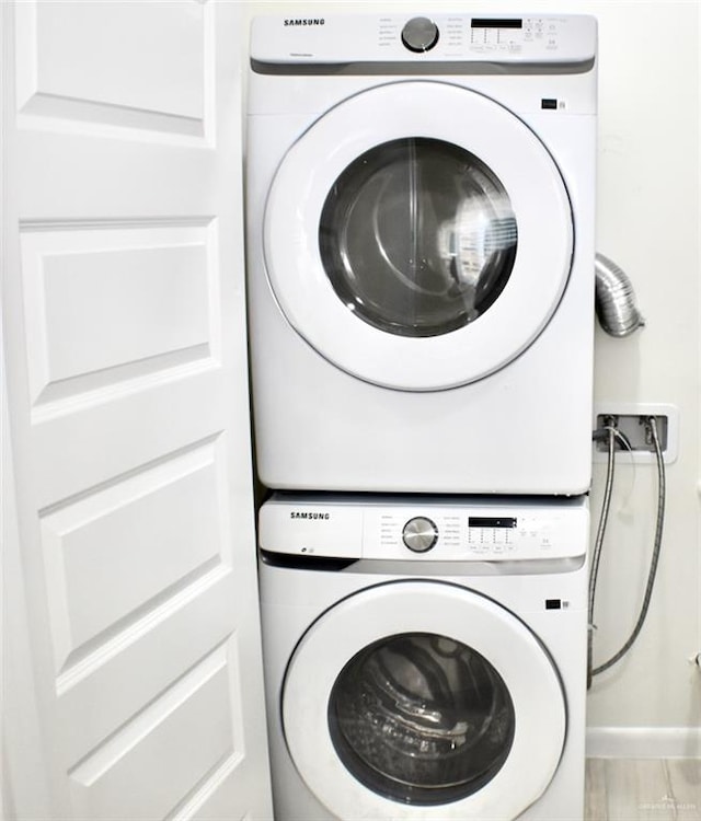 clothes washing area featuring stacked washer and clothes dryer and light wood-type flooring