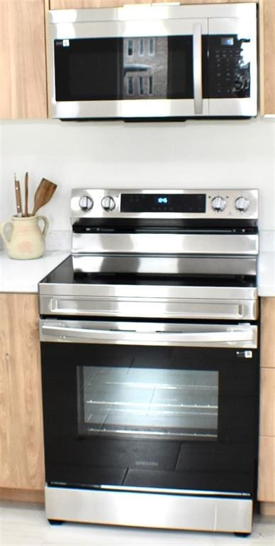 room details featuring light brown cabinets and appliances with stainless steel finishes