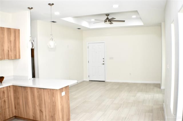 kitchen featuring pendant lighting, a raised ceiling, ceiling fan, light hardwood / wood-style floors, and kitchen peninsula