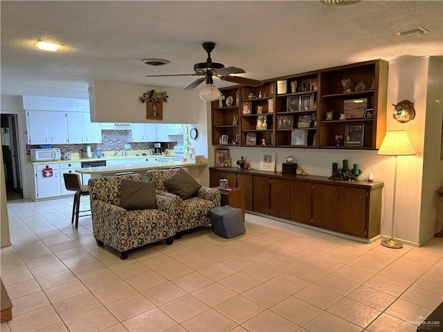 tiled living room featuring sink, a textured ceiling, and ceiling fan