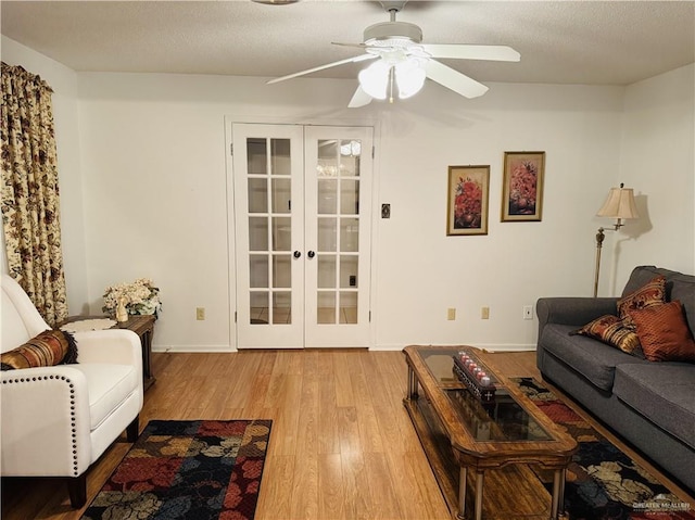 living room featuring ceiling fan, a textured ceiling, light wood-type flooring, and french doors