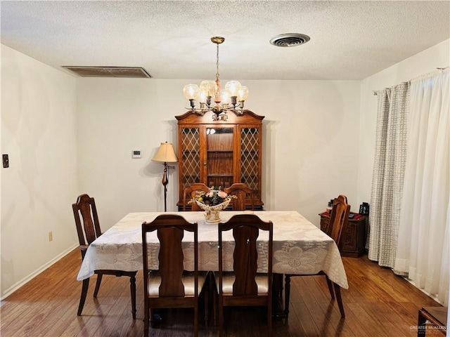 dining area featuring dark hardwood / wood-style flooring, a notable chandelier, and a textured ceiling