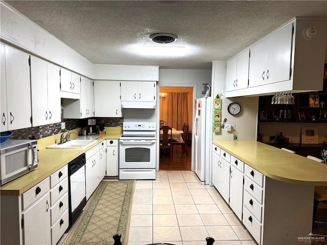 kitchen featuring sink, white appliances, white cabinetry, backsplash, and kitchen peninsula